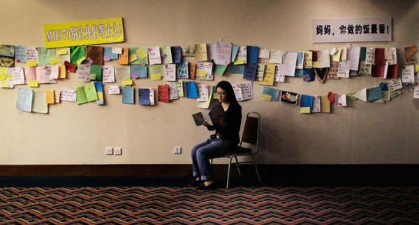 Bai Jie, daughter of Hou Aiqin, a passenger on missing Malaysian Airlines Flight MH370, reads some cards that were made by more than 40 people from Taiwan to give their wishes to those on the missing airline. Photo by ZHU XINGXIN / CHINA DAILY  