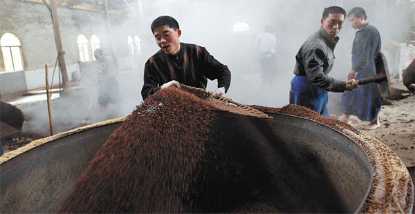 Observing centuries-old techniques and traditions, workers prepare sorghum for a 40-day fermentation process. [Photo by Zhang Wei / China Daily]