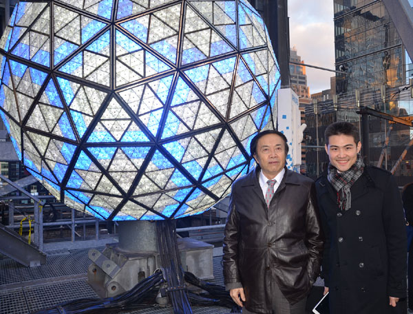 Chinese artist Yuan Xikun (left), from Yunnan province, and his son stand in front of the New Year Crystal Ball in Times Square in New York on Tuesday. Yuan's artworks are now being displayed on a screen in Times Square.Yunnan province will present a performance featuring its culture and tourism resources in Times Square Countdown on New Year's Eve. Lu Huiquan/for China Daily.