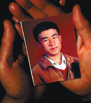 Hugjiltu's mother, Shang Aiyun, holds a photo of her son, who was wrongfully executed 18 years ago. [Photo by Guo Tieliu/for China Daily]