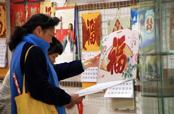 People examine calenders at a wholesale calendar market in Guangzhou, Guangdong province. [Photo Provided to China Daily]