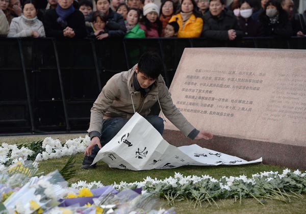 A young man places mourning couplets at Chen Yi Square in the Bund, site of the tragedy on New Years Eve that claimed 36 lives. LAI XINLIN FOR CHINA DAILY