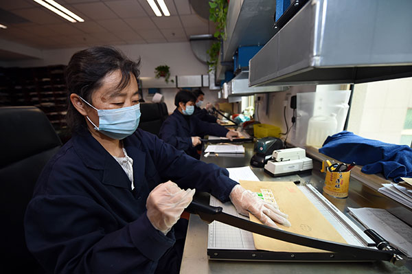 Workers open letters by paper cutters. [Photo/ CCDI website]  