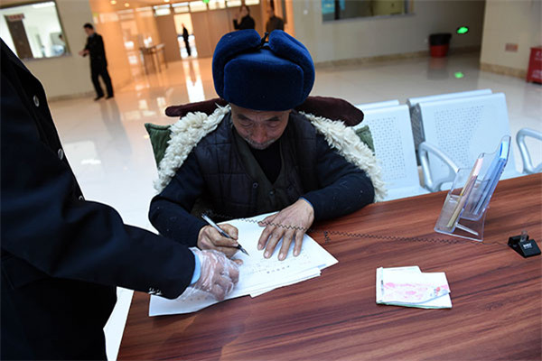 A man fills the registration form with the help of an official at the office. [Photo/ CCDI website]  