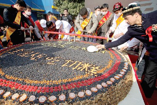 Let them eat cake: Adili Maimaititure (right) invites people in Changsha, capital of Hunan province, to taste a 2,015 kg Xinjiang nut cake made by his company. He Wenbing / for China Daily  