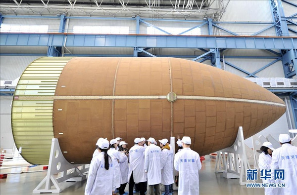 Photo taken on Dec 12, 2014 shows staff members check the fairing of the Long March-5 rocket.  (Xinhua/ Yue Yue)