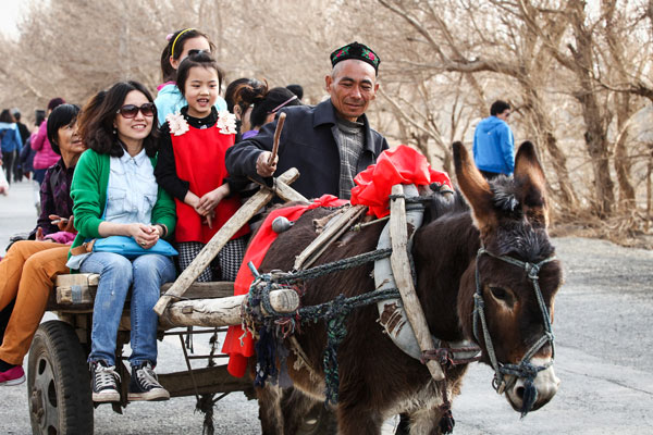 Tourists on a donkey cart in Turpan in March. This popular tourist location in the Xinjiang Uygur autonomous region will benefit from China-led new development initiatives designed to inject new impetus in key regions in western China. LIU JIAN/CHINA DAILY  