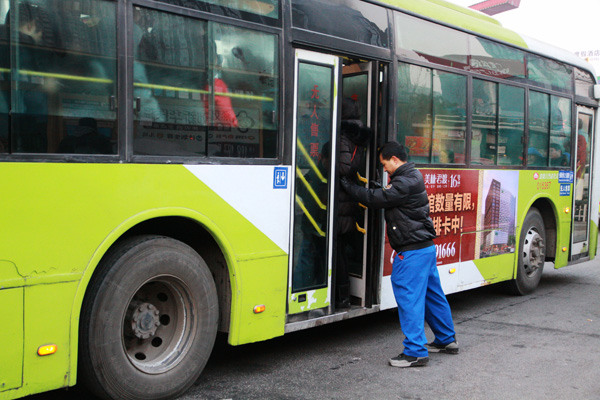 A bus employee pushes a passenger into the vehicle so that the rear door can close, Jan 12, 2015. [Photo by Song Wei/chinadaily.com.cn]  