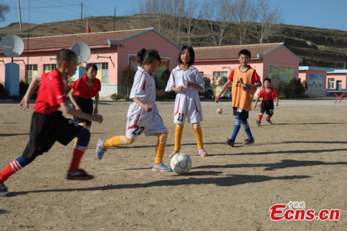 Students play football on a playground of a rural primary school in Yuzhong county, Gansu province on November 14, 2014. [Photo/ Liu Yutao]