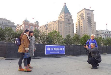 A man takes a photograph yesterday on the sightseeing platform at the Bund, close to the scene of the New Years Eve tragedy that left 36 people dead and 49 injured. The sign in the background directs people to the stairs from the platform.  Wang Rongjiang