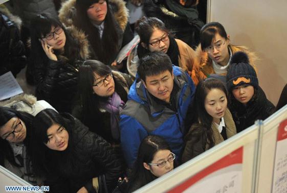 Job seekers look at employment information at a job fair for postgraduates in Beijing, capital of China, Dec 18, 2014. About 18,000 opportunities were offered at the fair.[Photo/Xinhua]