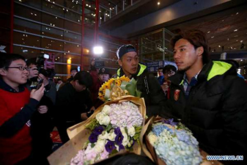 Wang Dalei (C) and Zhang Linpeng (R) of the Chinese national soccer team arrive at Beijing International Airport on Jan. 24, 2015. The team received a warm welcome at the airport early Saturday morning after their quarter-final loss in the Asian Cup.(Photo source: Xinhua)