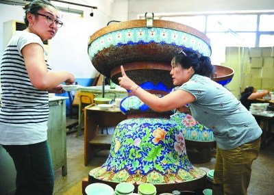 Luo (R) communicates with one of her apprentices (L) during work. [Photo/the Beijing Evening News]