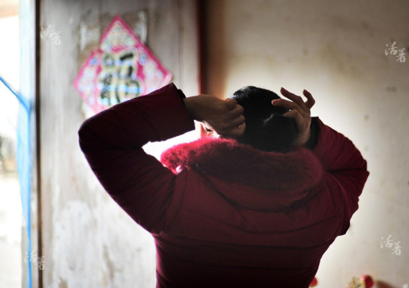 Yu Xiuhua binds up her hair in the morning on Jan 17, 2015. [Photo/China Daily] 