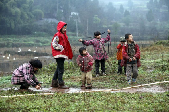 A picture taken in January shows six of He Hong's children playing on uncultivated land near their house. [Photo: China Daily]