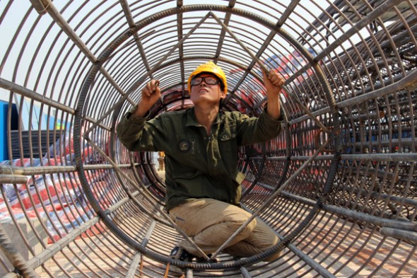 A worker checks a bridge reinforcement at a construction site of the Yiyang-Loudi Highway in Central China's Hunan province. China's GDP growth slowed to 7.4 percent in 2014, the lowest reading since 1990. [Li Aiming / China Daily]