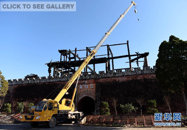A crane is seen parked in front of the burnt "Gongchenlou", an ancient architecture built in Ming Dynasty (1368-1644), in Weishan County, southwest China's Yunnan province, Jan 3, 2015. A fire broke out on the building early on Saturday and was extinguished two hours later. No casualties has so far been reported. (Xinhua/Lin Yiguang)