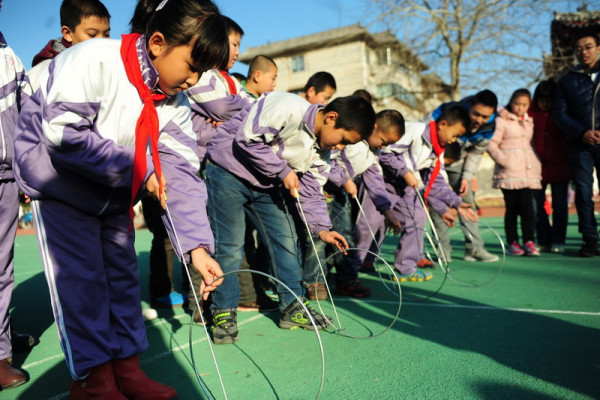 With a V-shaped iron bar or wire in their hands, the children roll forward a hoop, carefully keeping it balanced upright. Chinese children often have hoop rolling races. The photo shows primary school students learning to roll hoops at Dongguan Primary School of Nationalities in Liaocheng, Shandong province, Dec 9, 2013.[Photo/Zhang Zhenxiang/asianewsphoto.com]