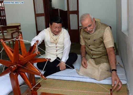 Chinese President Xi Jinping (L) rotates a spinning wheel that was once used by Mahatma Gandhi as he visits Gandhi's former residence along with Indian Prime Minister Narendra Modi in Gujarat, India, Sept 17, 2014. [Photo/Xinhua]  