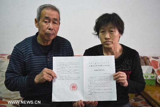 Li Sanren (L) and Shang Aiyun, parents of Huugjilt, who was wrongly executed for rape and murder at age 18, show the verdict of state compensation totaling more than 2 million yuan (about $322,000) in Hohhot, capital of north China's Inner Mongolia Autonomous Region, on Dec 31, 2014. [Photo/Xinhua]  