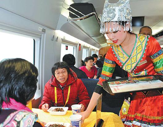 A train attendant wearing the traditional clothing of the Miao ethnic group serves passengers on the Guiyang-Guangzhou high-speed railway in December. Cao Ning / For China Daily  