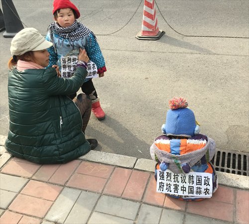 A female protester and two children, with banners saying strongly protesting against South Korean government for hurting the interests of Chinese garlic farmers and I want to eat and go to school. Photo: Liu Xin/GT