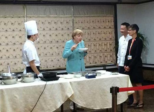 German Chancellor Angela Merkel eats kung pao chicken, a spicy Sichuan dish made with chicken, peanuts, vegetables, and chili peppers, at a Sichuan restaurant during her visit to Chengdu, July 6, 2014.  [Photo provided to China Daily]