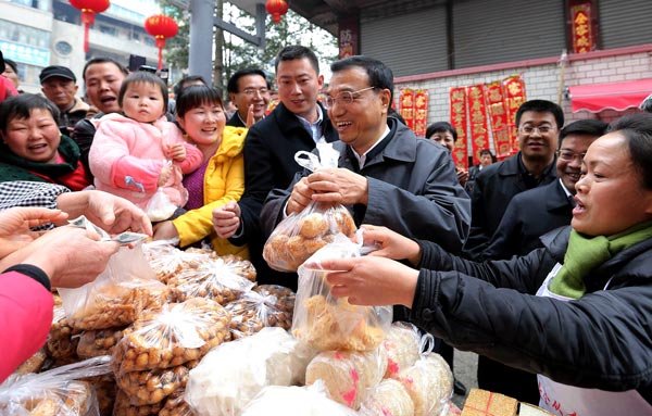 Premier Li Keqiang buys fried sticky rice with a sweet coating at a market in Liping county in the Qiandongnan Miao and Dong autonomous prefecture of Guizhou province on Friday. Liu ZhenIU ZHEN / China News Service
