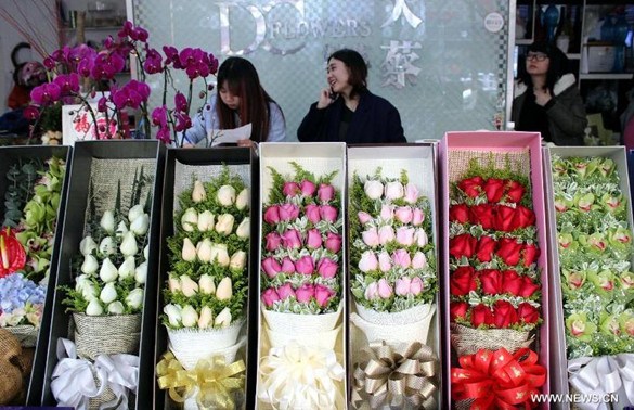 A waitress answers phonecalls for flowers reservation at a flower store in Suzhou, east China's Jiangsu Province, Feb. 13, 2015. (Xinhua/Wang Jiankang)