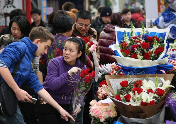 A foreigner asks about the price of roses at Laitai Flower Market in Beijing on Feb 13, 2014 ahead of Valentine's Day on Feb 14. [Photo by Wang Zhuangfei/ China Daily]