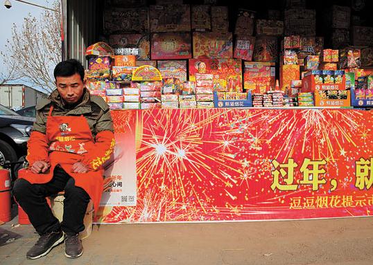 A salesman waits for customers at a fireworks retail outlet in Beijing's Chaoyang district on Saturday. WANG JING / CHINA DAILY  
