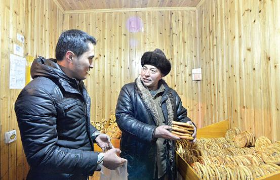 Turgonjan Maola (right) now works as an assistant at his son's nan shop in Xinjiang. His son, Dalixat, continues the family's nan business, and he helps his father to track down the two landlords in Suzhou and Shanghai. Shan Kun / for China Daily  
