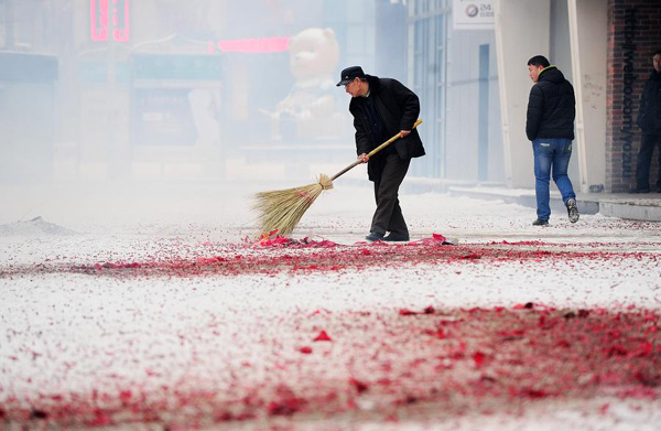 A resident cleans remains of firecrackers in Yinchuan, Ningxia Hui aotonomous region, Feb 7, 2014. (Photo/Xinhua)