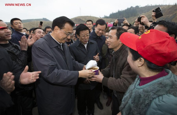 Chinese Premier Li Keqiang, also a member of the Standing Committee of the Political Bureau of the Communist Party of China (CPC) Central Committee, hands a cup of instant noodle to a migrant worker who is on his way home at Zhongchao service zone on Liluo expressway in southwest China's Guizhou Province, Feb. 14, 2015. (Xinhua/Huang Jingwen) 