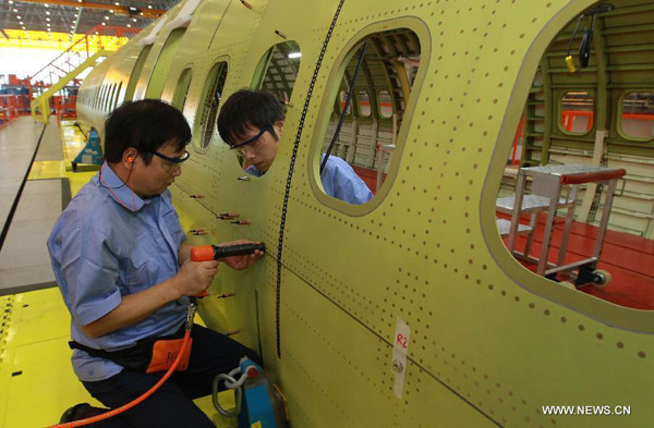 File photo shows technicians installing rivets on fuselage of C919 airliner in the assembly base of the Commercial Aircraft Corp. of China (COMAC) in Shanghai, Sept 19, 2014. (Photo/Xinhua)
