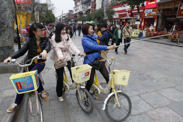 Three young women take photos with a selfie stick on a street in Yangshuo, a well-known tourist resort in Guilin, Guangxi Zhuang autonomous region in Southwest China. Selfie sticks, also known as Shen'gun, are as popular in China as any other smartphone market. Photo by Huo Yan / China Daily