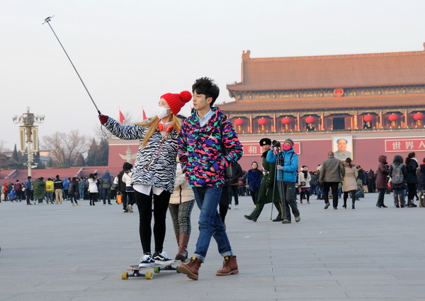 A couple take a photo with a selfie stick at the Tian'anmen Square in Beijing. Provided to China Daily