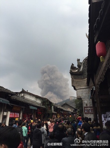 Black smoke is seen while crowds of tourists gather in Luodai, a tourist town in Southwest China's Sichuan province after an explosion occured at a nearby tunnel construction site, Feb 24, 2015. Chengdu Economic Daily posted the photo on SinaWeibo. (Photo/SinaWeibo)