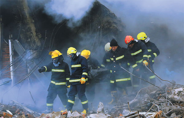 Firefighters carry the body of a dead colleague on a stretcher after a warehouse fire in the northeastern city of Harbin in Heilongjiang province in January. Five firefighters died fighting the blaze and 14 people were injured. (Photo: Xiao Jingbiao/For China Daily)