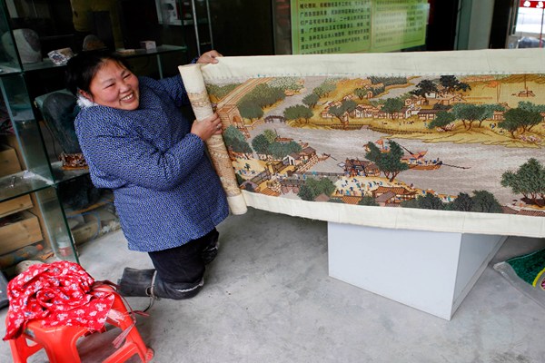 Hu Fenglian displays an embroidery painting she made. (Huo Yan/China Daily)