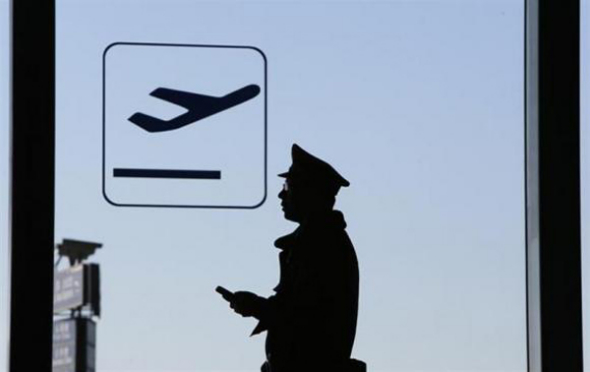 A policeman is silhouetted inside Beijing International Airport, March 13, 2014. [Photo/China Daily]