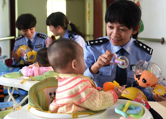 Police officers visit babies, rescued from kidnappers, at an orphanage in Kunming, Yunnan province. Kunming police saved 11 babies after breaking up a gang of kidnappers that targeted babies in November. (Photo: Xinhua/Lin Yiguang)