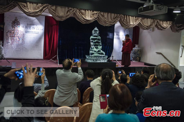 Visitors take photos of an ice Buddha sculpture, made from a mix of glacier water from the Himalayas and flowing water from Taiwan during an exhibition in Taipei, Feb 15, 2015. More than 80 Buddhism-themed fine art works by 30 leading Tibetan artists are open to the public in Taipei on Sunday. [Photo: China News Service/Kang Fangrong] 