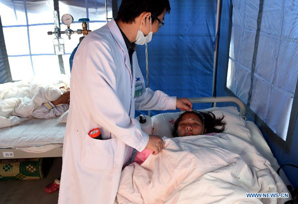 Injured girl Jing'e receives medical treatment from a doctor in a health center in Mengding Township of Gengma Dai and Wa Autonomous County, southwest China's Yunnan Province, March 2, 2015. Thirty-two people have been injured after a 5.5 magnitude earthquake struck Cangyuan County of Yunnan Province at 6:24 p.m (1024GMT) on Sunday. (Xinhua/Lin Yiguang)