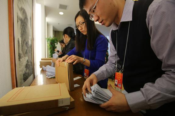 Staff members in the secretarial department of the National People's Congress collect motions from deputies. As of noon on Tuesday, 54 more motions had been submitted than during last year's session. (Photo: China Daily/Wang Jing)