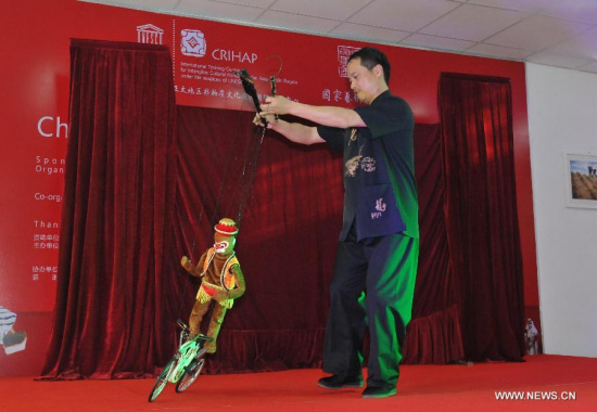 A puppeteer pulls strings on a stage in Phnom Penh, Cambodia, March 11, 2015. An eight-member troupe of China's Fujian puppetry practitioners performed traditional puppetry here on Wednesday to promote cultural ties between the two countries. (Xinhua/Li Hong)
