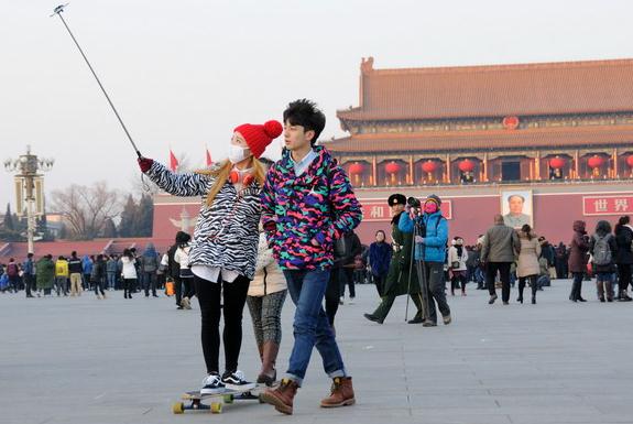 A couple take a photo with a selfie stick at the Tian'anmen Square in Beijing. (Photo/Provided to China Daily)  