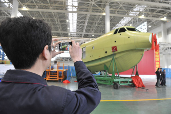 A worker photographs the front of the fuselage of China's first domestically developed seaplane in Chengdu on Tuesday. The AG-600 will become the world's largest amphibious aircraft, surpassing Japan's ShinMaywa US-2 and Russia's Beriev Be-200. Wu Xiaochuan / For China Daily
