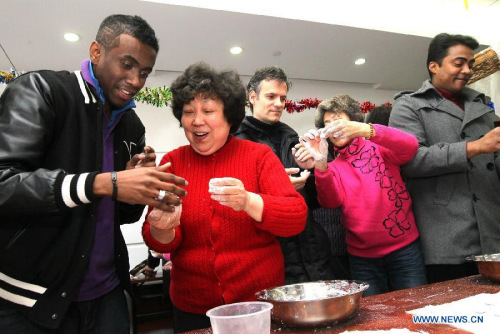 Ma Liang (1st L) from Madagascar learns to make the Yuanxiao, glutinous rice flour dumpling with sweetened stuffing, at a community in Shanghai, east China, Feb. 21, 2013. (Xinhua/Chen Fei)