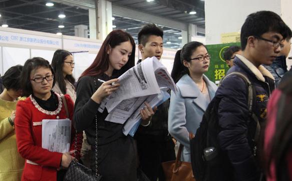 Job seekers hand in their resumes at a job fair in Hangzhou on Tuesday. A newly released report said graduates from domestic colleges are being favored over those who studied overseas. (Photo: Hu Yuanyong/For China Daily)